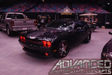 Three quarters view of a black Dodge Challenger in a showroom, with red LED headlight and fog light halo rings installed.