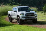 Three quarters view of a Toyota Tacoma with green headlight DRLs.