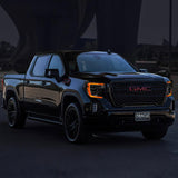 Three quarters view of a black GMC Sierra with amber headlight DRLs.