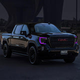 Three quarters view of a black GMC Sierra with purple headlight DRLs.