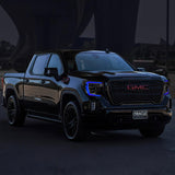 Three quarters view of a black GMC Sierra with blue headlight DRLs.