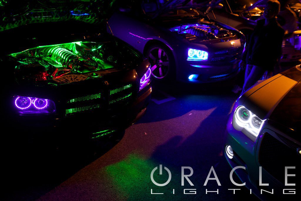 Car meet with engine bays open and LED lighting.