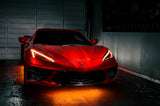 Red Corvette in a garage with amber headlight DRLs.