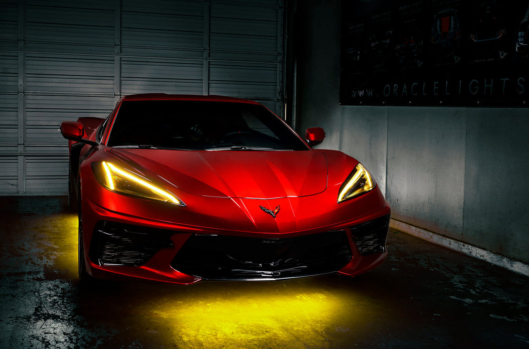 Red Corvette in a garage with yellow headlight DRLs.