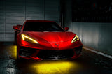 Red Corvette in a garage with yellow headlight DRLs.