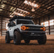White Ford Bronco in a large barn, with amber Oculus Headlights installed.