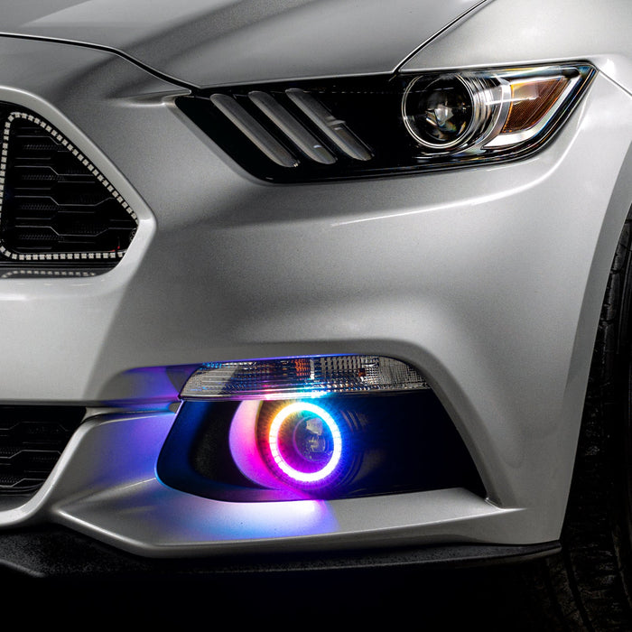 Close-up on the front bumper of a silver Ford Mustang equipped with rainbow fog light halos.
