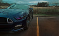 Close-up of a Ford Mustang headlight with rainbow halos and DRLs.