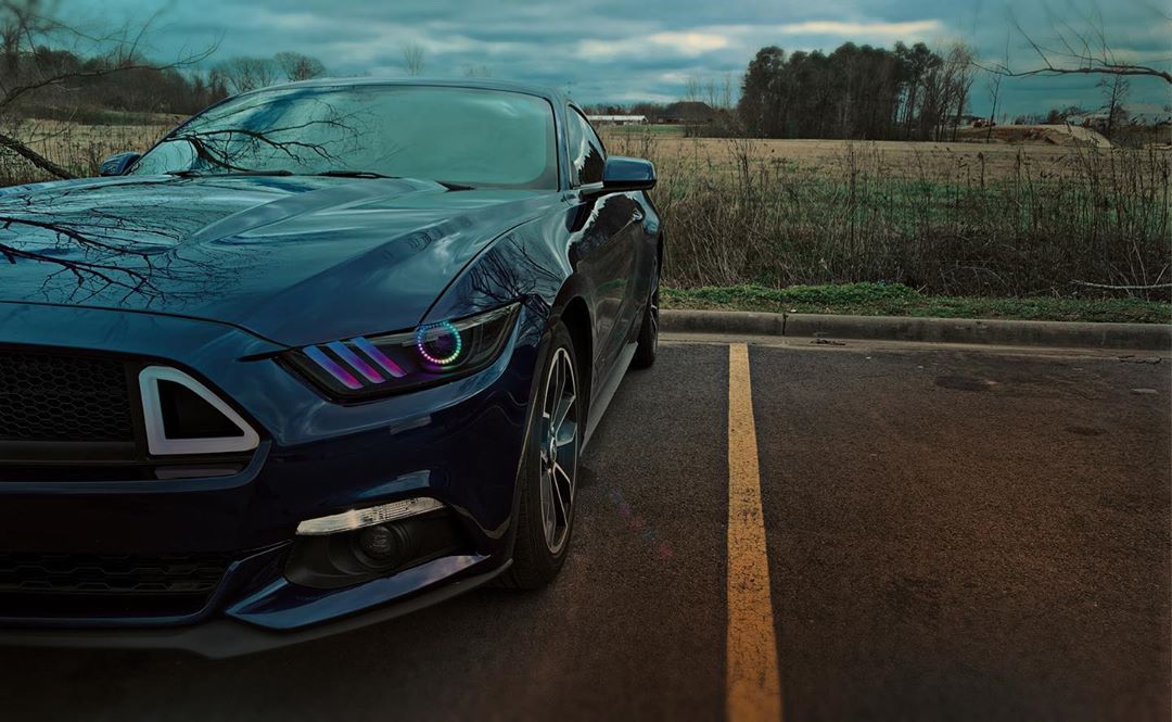 Close-up of a Ford Mustang headlight with rainbow halos and DRLs.
