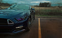 Close-up of a Ford Mustang headlight with rainbow halos and DRLs.