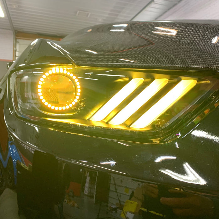 Close-up on a Ford Mustang headlight with yellow halos and DRLs.