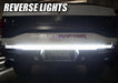 Rear view of a Ford Raptor with 60” Double Row LED Truck Tailgate Light Bar installed and reverse lights on.