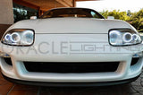 Front end of a Toyota Supra with white LED headlight halos installed.